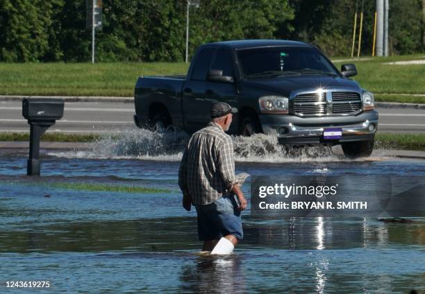 Man walks through his front yard as a creek rises from flooding following Hurricane Ian on September 30, 2022 in Kissimmee, Florida. - Forecasters...