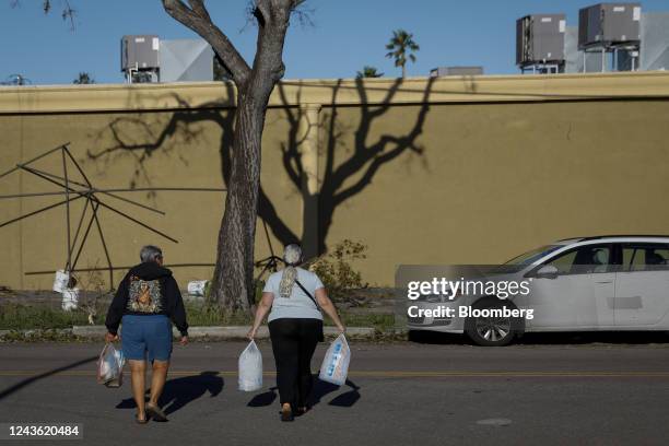 Pedestrians carry bags of ice and groceries following Hurricane Ian in Cape Coral, Florida, US, on Friday, Sept. 30, 2022. Two million electricity...