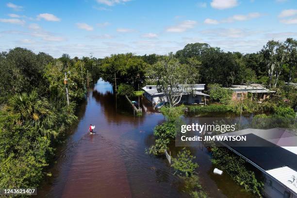 In this aerial view, a person carries a garbage bag of belongings through the flooded street of their neighborhood in New Smyrna Beach, Florida, on...