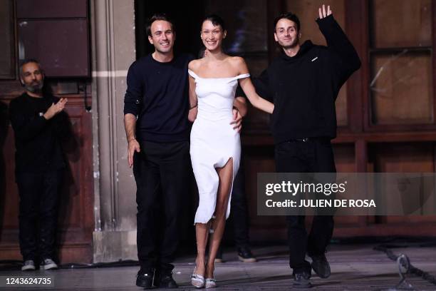 French designers Sebastien Meyer and Arnaud Vaillant lead US model Bella Hadid dressed in a Fabrican Spray-on fabric slip dress as they acknowledge...