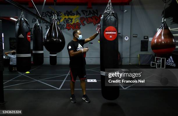 Member of staff wearing a mask and protective gloves sprays disinfectant on punching bags at the Real Boxing Only Gym on June 3, 2020 in Dubai,...