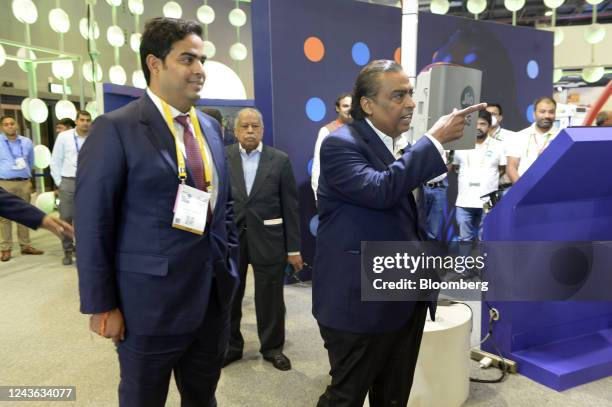 Mukesh Ambani, chairman of Reliance Industries Ltd., right, with his son Akash Ambani, chairman of Reliance Jio Infocomm Ltd., visit a company's...