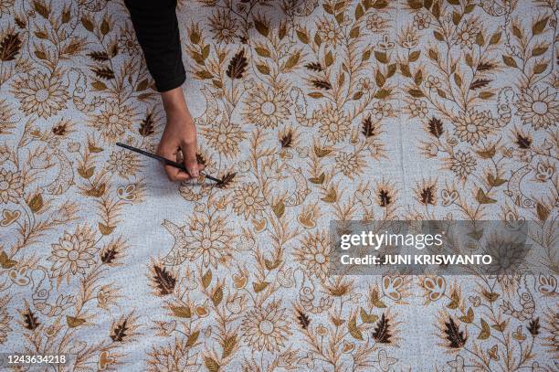 Worker colours batik cloth, a traditional textile made using wax-resist dyeing methods, in Sidoarjo on October 1 on the eve of Indonesia's National...
