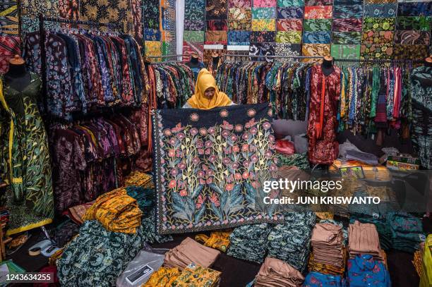 Woman shows a piece of batik cloth, a traditional textile made using wax-resist dyeing methods, at a showroom in Sidoarjo on October 1 on the eve of...