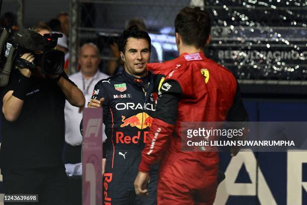 Ferrari's Monegasque driver Charles Leclerc greets Red Bull Racing's Mexican driver Sergio Perez after the qualifying session ahead of the Formula...