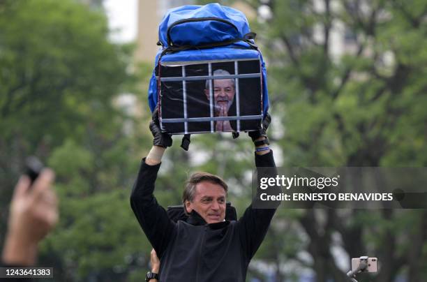 Brazilian President and re-election candidate Jair Bolsonaro holds a bag with the image of former President and presidential candidate for the...