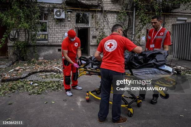 Red Cross rescuers carry the body of woman killed in a residential building which was shelled in the city of Mykolaiv, on October 1 amid the Russian...