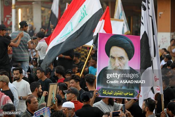 Iraqi protesters lift placards and national flags during a rally to mark three years since nationwide demonstrations erupted against endemic...