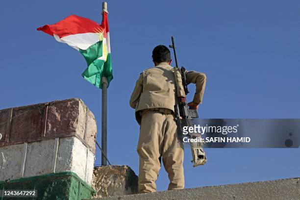 Kurdish peshmerga fighter affiliated with the Iranian Kurdistan Democratic Party stands guard on a building following an Iranian cross-border attack...