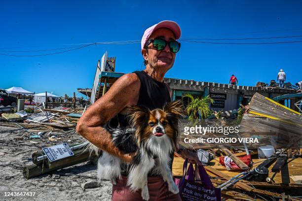 Resident holds her pet as she walks past debris on San Carlos Island in Fort Myers, Florida, in the aftermath of Hurricane Ian on October 1, 2022. -...
