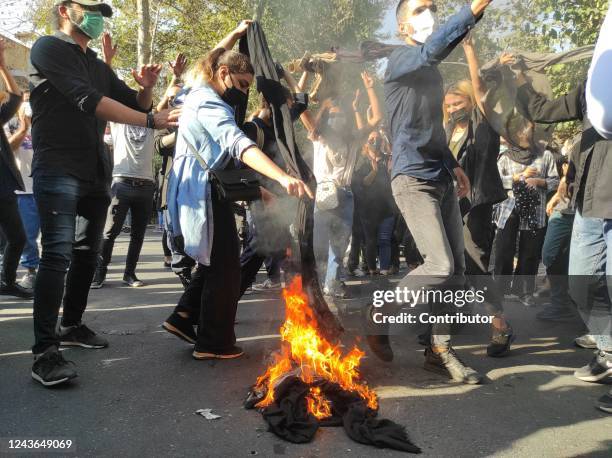 Iranian protesters set their scarves on fire while marching down a street on October 1, 2022 in Tehran, Iran. Protests over the death of 22-year-old...