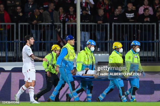 Milan's Italian midfielder Sandro Tonali escorts AC Milan's Italian defender Davide Calabria as he is carried away from the pitch after being injured...