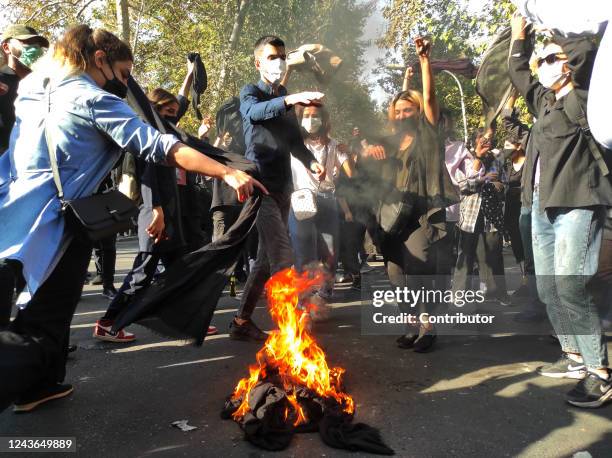 Iranian protesters set their scarves on fire while marching down a street on October 1, 2022 in Tehran, Iran. Protests over the death of 22-year-old...