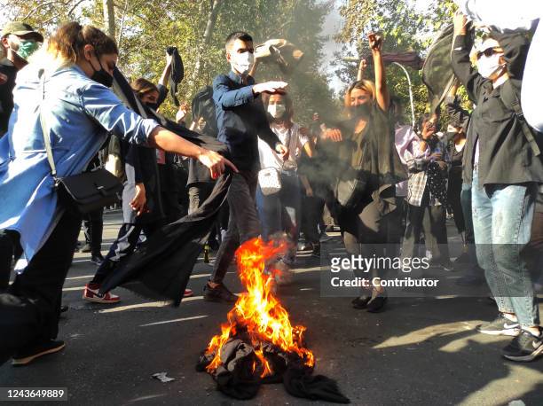 Iranian protesters set their scarves on fire while marching down a street on October 1, 2022 in Tehran, Iran. Protests over the death of 22-year-old...