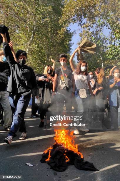 Iranian protesters set their scarves on fire while marching down a street on October 1, 2022 in Tehran, Iran. Protests over the death of 22-year-old...