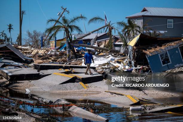 Man walks over a broken section of the Pine Island Road in the aftermath of Hurricane Ian in Matlacha, Florida on October 1, 2022. - Shocked Florida...