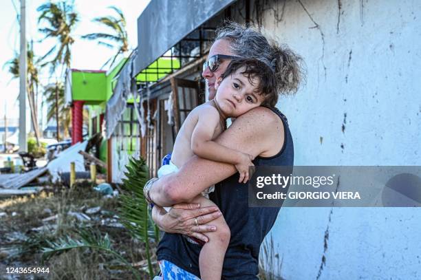 Woman of holds her grandson in arms outside their home in the aftermath of Hurricane Ian in San Carlos Island, Florida on October 1, 2022. - Shocked...