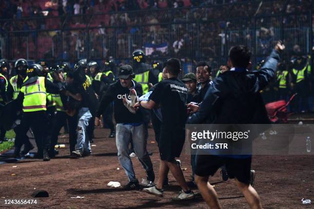 In this picture taken on October 1 a group of people carry a man after a football match between Arema FC and Persebaya Surabaya at Kanjuruhan stadium...