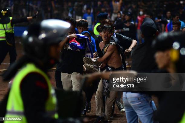 In this picture taken on October 1 a group of people carry a man after a football match between Arema FC and Persebaya Surabaya at Kanjuruhan stadium...