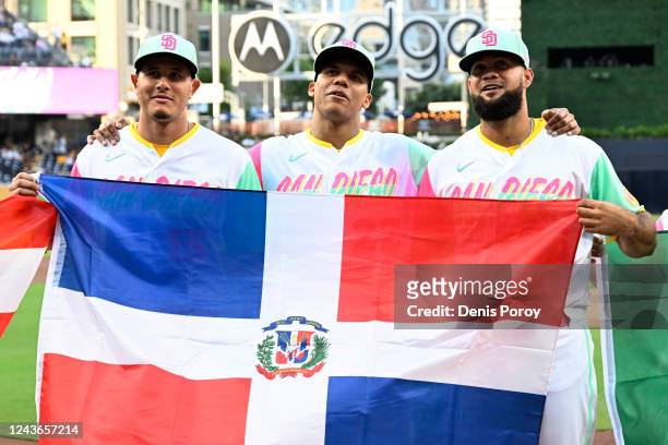 Manny Machado, Juan Soto, and Luis Garcia of the San Diego Padres hold the flag of the Dominican Republic before a baseball game against the Chicago...