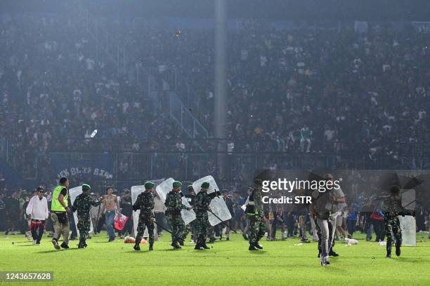 This picture taken on October 1, 2022 shows members of the Indonesian army securing the pitch after a football match between Arema FC and Persebaya...