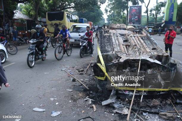 People pass near a damaged police vehicle is seen at Kanjuruhan Stadium in Malang, East Java Province, Indonesia, on 02 October 2022. At least 127...