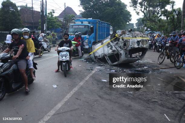 People pass by a damaged police vehicle outside Kanjuruhan stadium in Malang, East Java, Indonesia, on 02 October 2022. At least 127 people including...