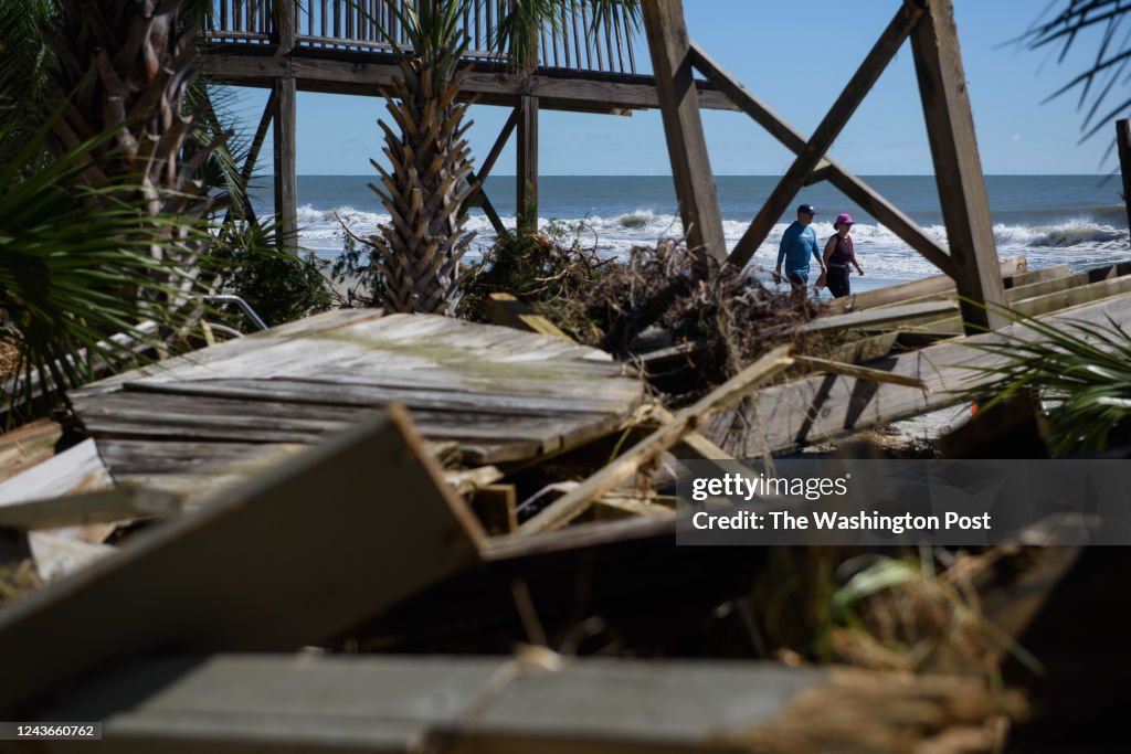 A couple walks past damage from Hurricane Ian on Litchfield Beach, SC