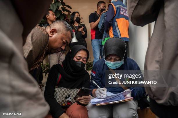 Police identifies relatives of victims as they queue their bodies in Malang, East Java on October 2, 2022. - At least 174 people died at an...