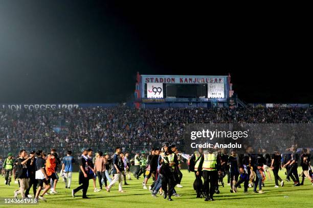 Football supporters enter the pitch as security officers try to disperse them during a riot following a soccer match at Kanjuruhan Stadium in Malang,...