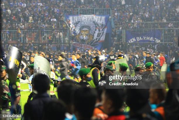 Football supporters enter the pitch as security officers try to disperse them during a riot following a soccer match at Kanjuruhan Stadium in Malang,...