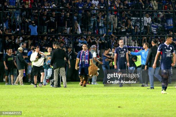 Football supporters enter the pitch as security officers try to disperse them during a riot following a soccer match at Kanjuruhan Stadium in Malang,...