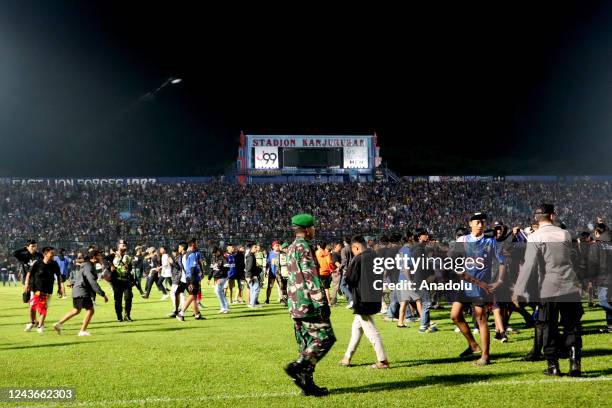 Football supporters enter the pitch as security officers try to disperse them during a riot following a soccer match at Kanjuruhan Stadium in Malang,...