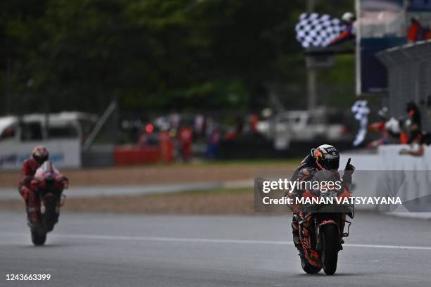 Red Bull KTM Factory Racing's Portuguese rider Miguel Oliveira celebrates winning the MotoGP Thailand Grand Prix in front of Ducati Lenovo's...