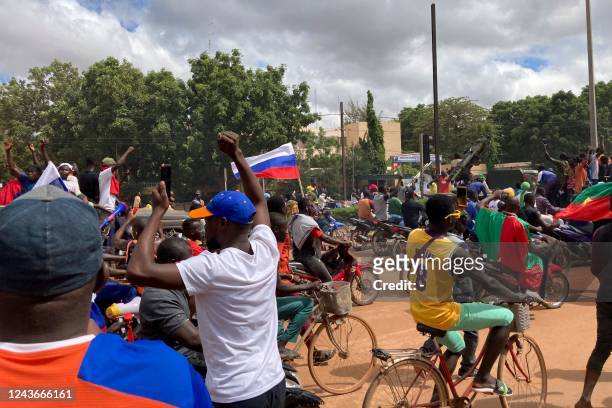 Protesters march carrying Russian flags in Ouagadougou on October 2, 2022. - Security forces fired tear gas to disperse angry protesters outside the...