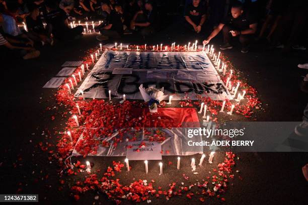 People light candles during a candlelight vigil to show their condolences to victims of a stampede, in Jakarta on October 2, 2022. - At least 127...