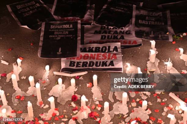 Banners reading Indonesian football mourning are placed next to the candles as football supporters named Ultras spray flower petals during a...