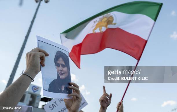 Protestors holds a photo of Kurdish Iranian woman Mahsa Amini as another waves Iran's former flag during a demonstration against the Iranian regime...