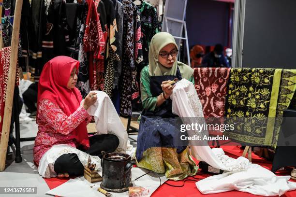 Women applied melted wax using the spouted tools called a canting as make traditional Indonesian batik during National Batik Day in Shopping Mall in...