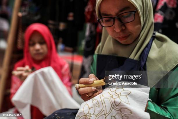 Women applied melted wax using the spouted tools called a canting as make traditional Indonesian batik during National Batik Day in Shopping Mall in...