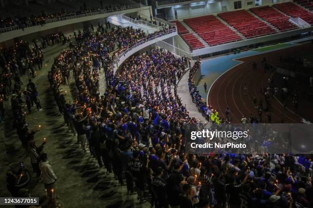 Football supporters gather and pray as a tribute to the victims of the riots in a soccer match at the Jatidiri Stadium in Semarang, Central Java...