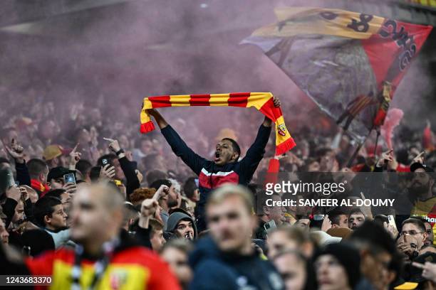 Lens supporter holds a scarf as he cheers during the French L1 football match between RC Lens and Olympique Lyonnais at Stade Bollaert-Delelis in...