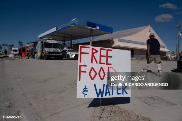 Man walks past a free food and water sign in the aftermath of Hurricane Ian in Fort Myers Beach, Florida on October 2, 2022. - The confirmed death...