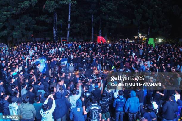This picture taken in Bandung on October 2, 2022 shows football supporters attending a candlelight vigil for victims of a stampede at Kanjuruhan...
