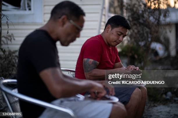 Jose Ramirez and Carlos Hernandez eat tacos for dinner in the aftermath of Hurricane Ian in Fort Myers Beach, Florida on October 2, 2022. - The...