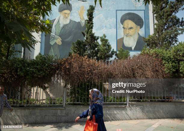 An Iranian woman walks under a mural with portraits of Irans Supreme leader Ayatollah Ali Khamenei and Late Leader Ayatollah Ruhollah Khomeini in...