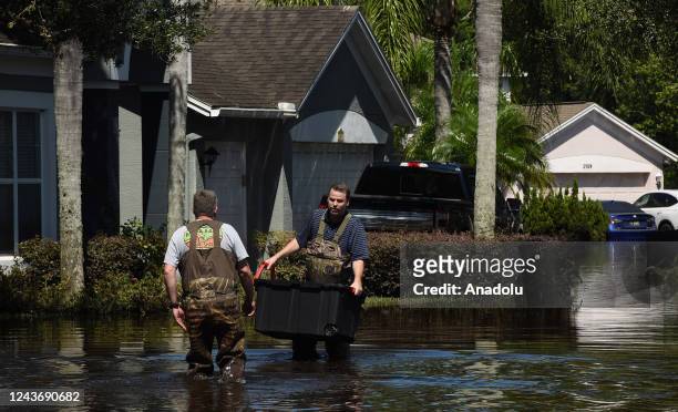 Two men wade through water to pick up items from a home flooded by rain from Hurricane Ian on October 1, 2022 in Orlando, Florida. The storm caused...