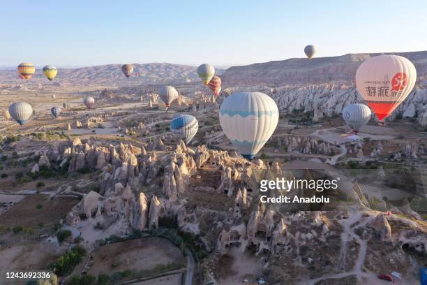 Hot air balloons glide over the sky at sunrise in Goreme district of Nevsehir, Turkiye on October 03, 2022. Hot air balloon tours providing a bird's...