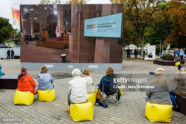 Passers-by watch the festive service on a screen for the German Unity Day celebrations in the city centre on October 3, 2022 in Erfurt, Germany. On 3...