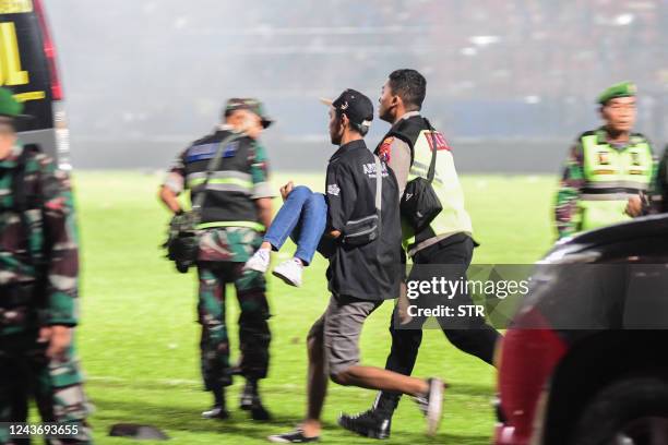 This picture taken on October 1, 2022 shows people running with an injured spectator after a football match between Arema FC and Persebaya at the...